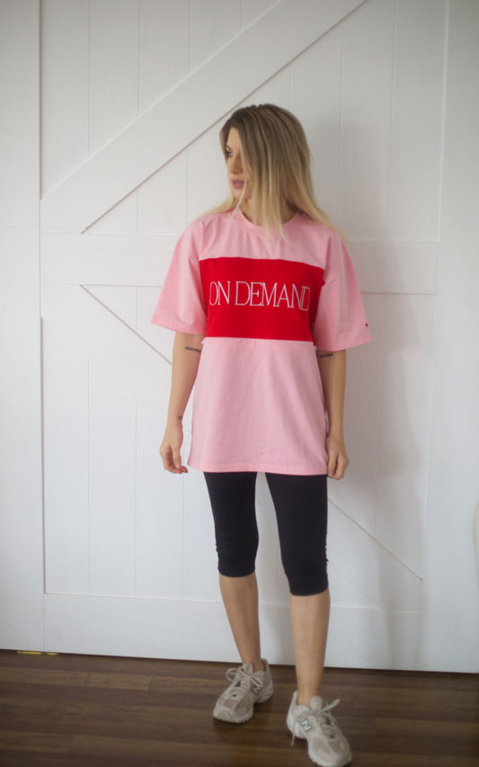 Front view of model wearing the pink breastfeeding t-shirt with red On Demand embroidered panel and relaxed oversized fit.